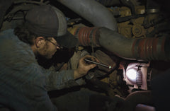 A mechanic inspecting a broken engine with an LED stainless steel penlight.