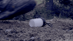 An animation of a man in hiking boots stepping on the plastic cover a lantern.