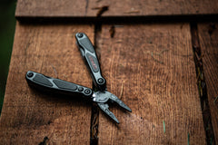 Black Spring Loaded Pliers Resting Open On Wood Surface with LED Light Turned On, lifestyle photo