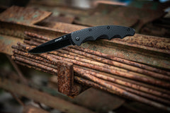 Black Stainless Steel Knife Resting Open on Rusty Steel Bars, lifestyle photo