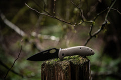 Stainless Steel Folding Knife Resting Open on Wooden Stump, lifestyle photo