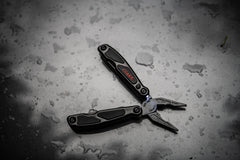 Black Spring Loaded Pliers Resting Open On Wet Dark Surface with LED Light Turned On, lifestyle photo