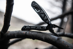 Black Spring Loaded Pliers Resting Open On Tree Branch with LED Light Turned On, lifestyle photo