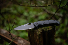 Stainless Steel Knife with Nylon Handle Resting Open on Tree Stump, lifestyle photo